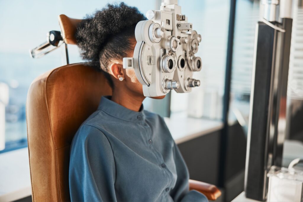 A patient looking through a phoropter during an eye exam.