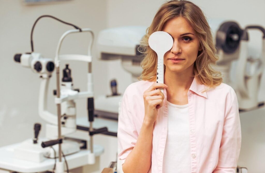 A patient at an eye exam holding an ocular shield over their eye to read an eye chart.